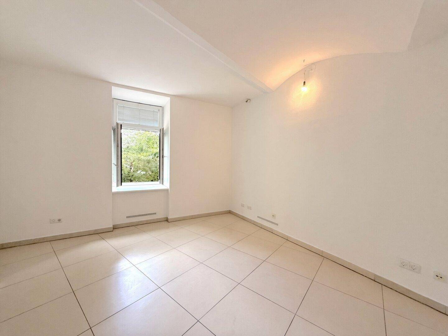 Heller Raum mit Fliesenboden und einem Fenster, das einen grünen Ausblick bietet.