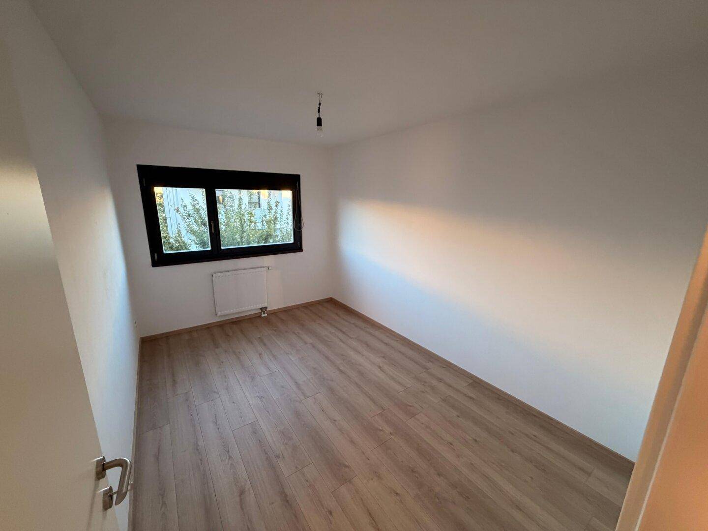Freundliches Zimmer mit Laminatboden und Fenster, das eine angenehme Wohnatmosphäre schafft.