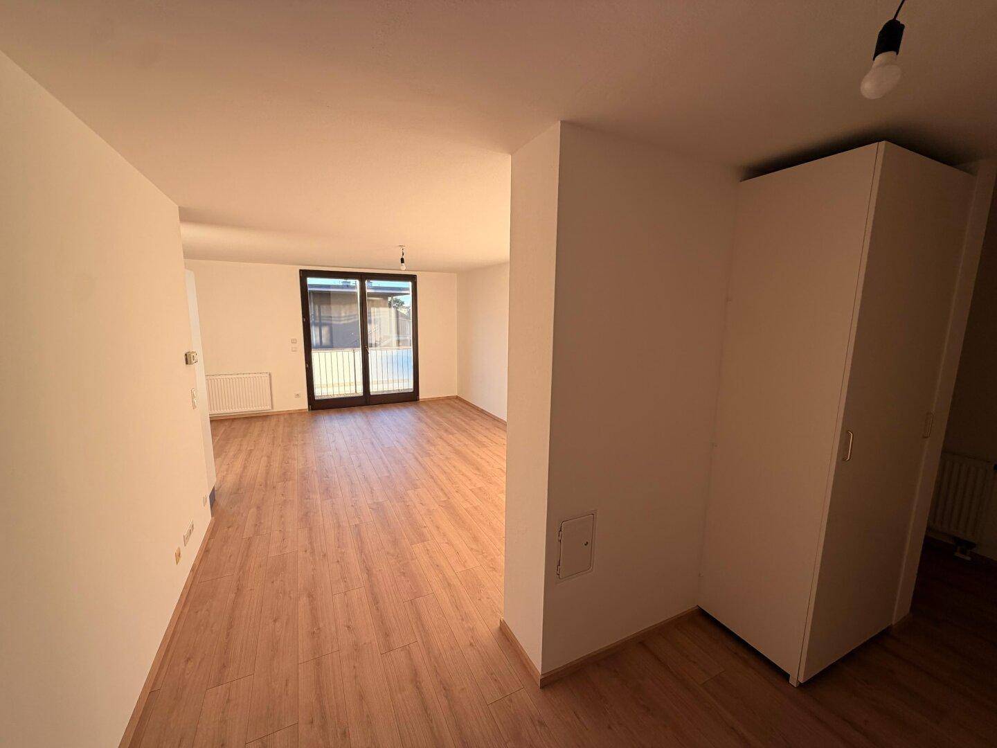 Geräumiges Wohnzimmer mit Laminatboden und Zugang zu einem Außenbereich, ideal für helle Einrichtung.
