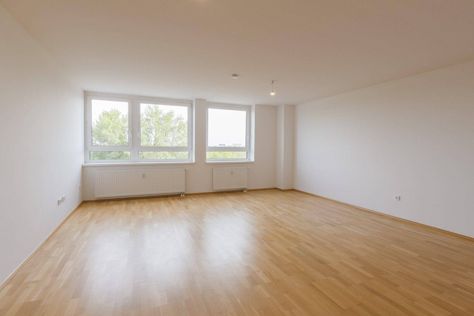 Geräumiges Zimmer mit hellem Parkettboden und mehreren Fenstern, ideal für vielfältige Nutzungsmöglichkeiten.