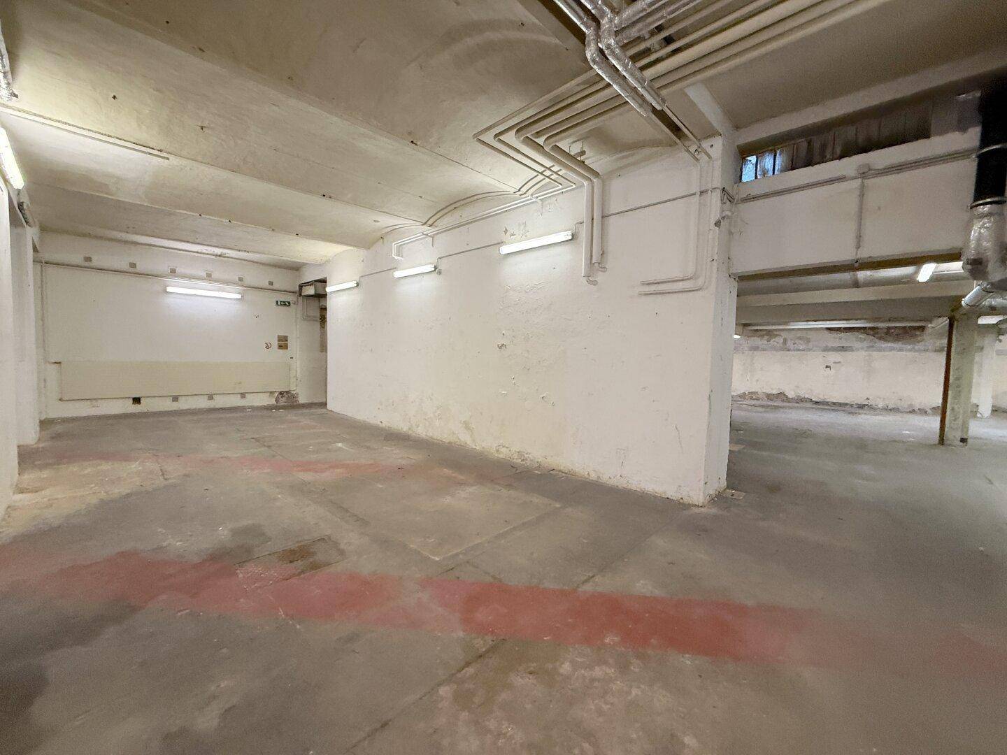 Geräumiger Gewerberaum mit Betonboden und freiliegenden Installationen, ideal für verschiedene Nutzungskonzepte.