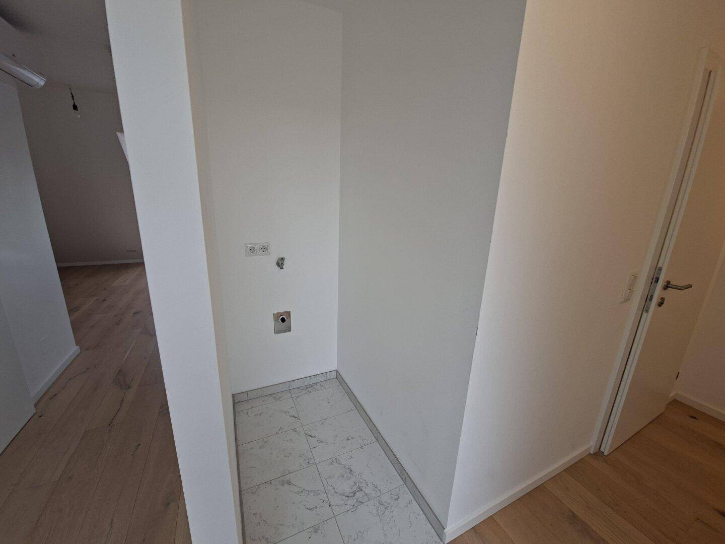 Kleiner Hauswirtschaftsraum mit Fliesenboden und Anschlüssen für Haushaltsgeräte.