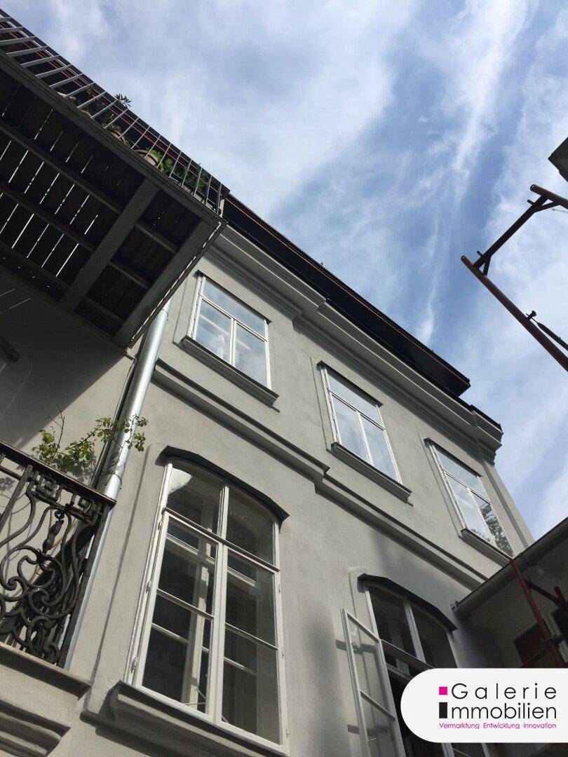 Historische Fassade eines Gebäudes mit klassischen Fenstern und einem kleinen Balkon.