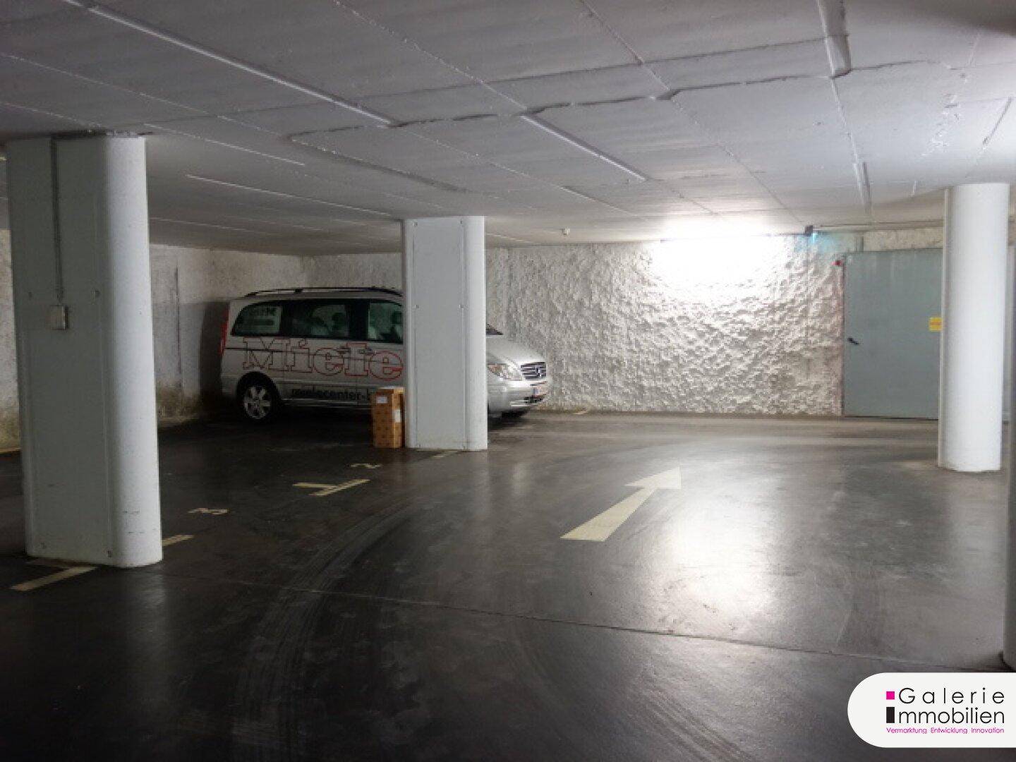 Weitere Ansicht der Tiefgarage mit markierten Stellplätzen und einem geparkten Fahrzeug, gut beleuchtet.
