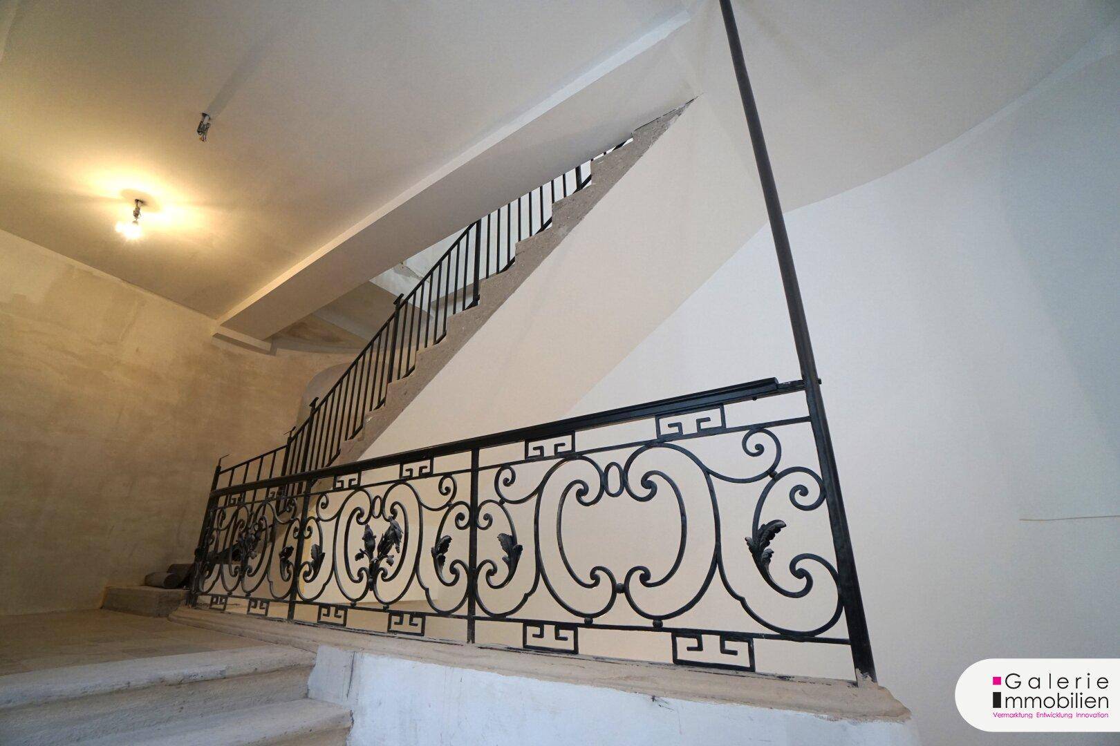 Elegantes Treppenhaus mit kunstvollem schmiedeeisernem Geländer und hohen Decken.
