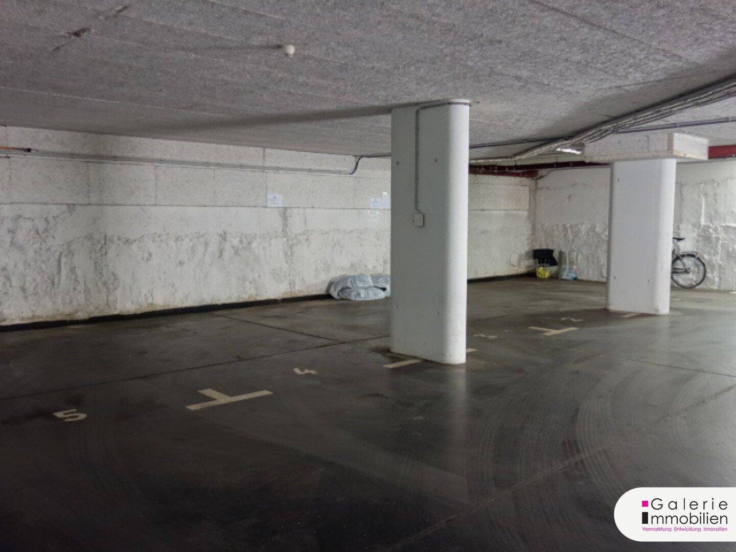 Leerer Bereich der Tiefgarage mit nummerierten Stellplätzen und einem Fahrrad, gut erhalten.