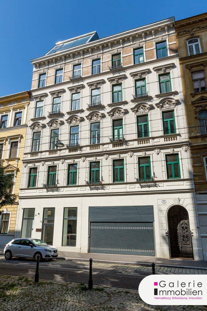 Historisches Mehrfamilienhaus mit klassischer Fassade und grünen Fensterläden in städtischer Umgebung.