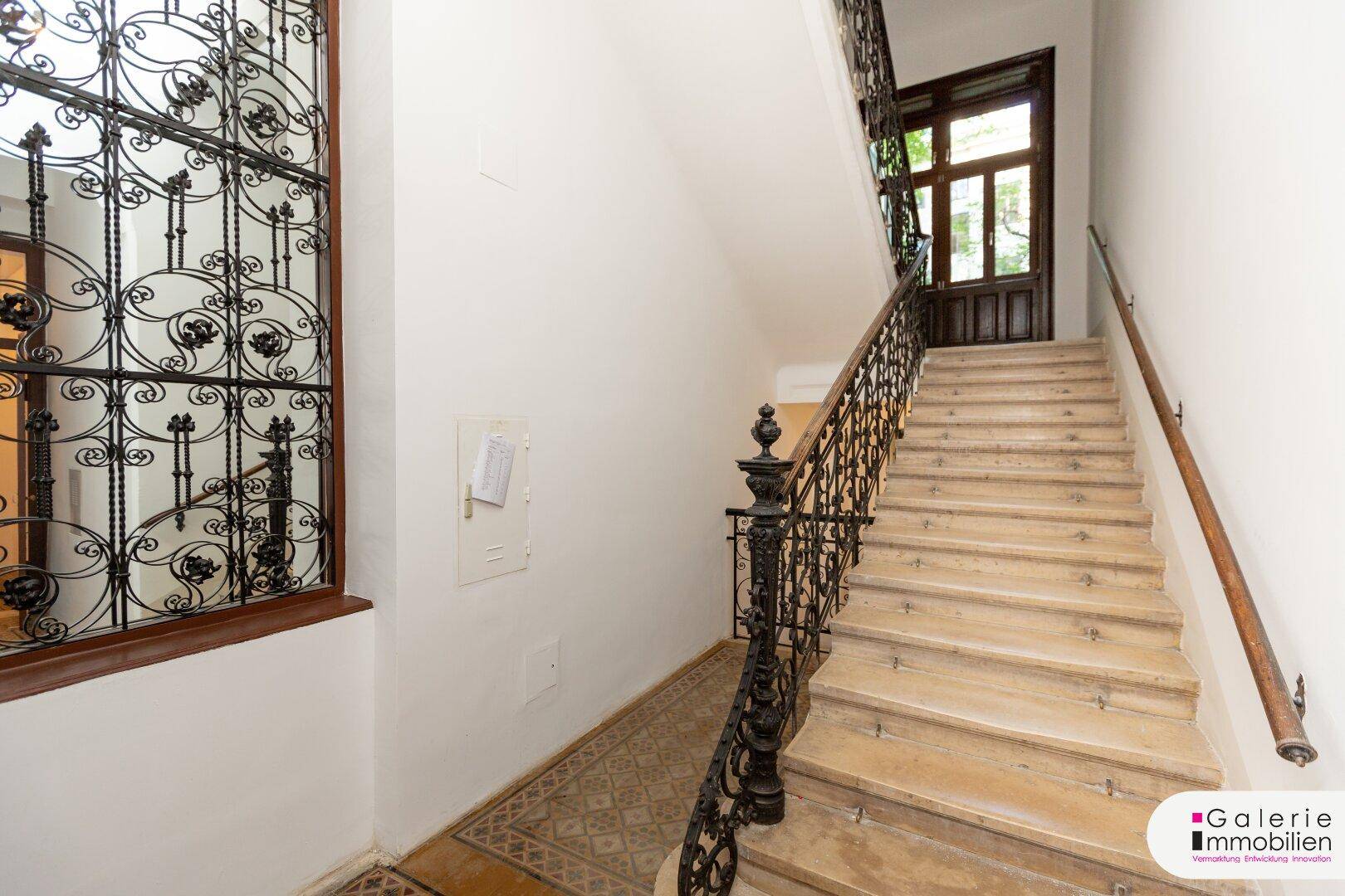 Helles Treppenhaus mit Marmorstufen und kunstvollem schmiedeeisernem Geländer.
