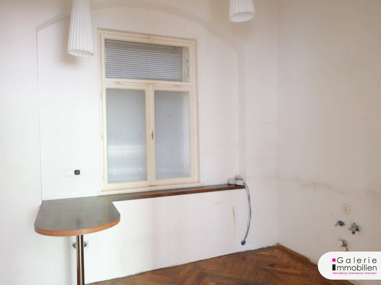 Kleine Küche mit Fenster, vorbereiteten Anschlüssen und einem Bartresen, der zur Renovierung einlädt.