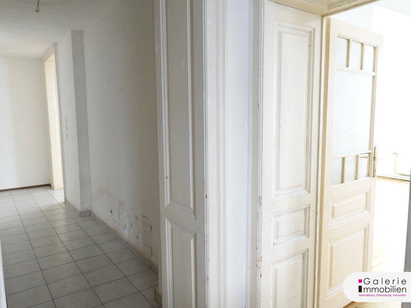 Flur mit Fliesenboden und traditionellen Holztüren, die zu verschiedenen Räumen führen.