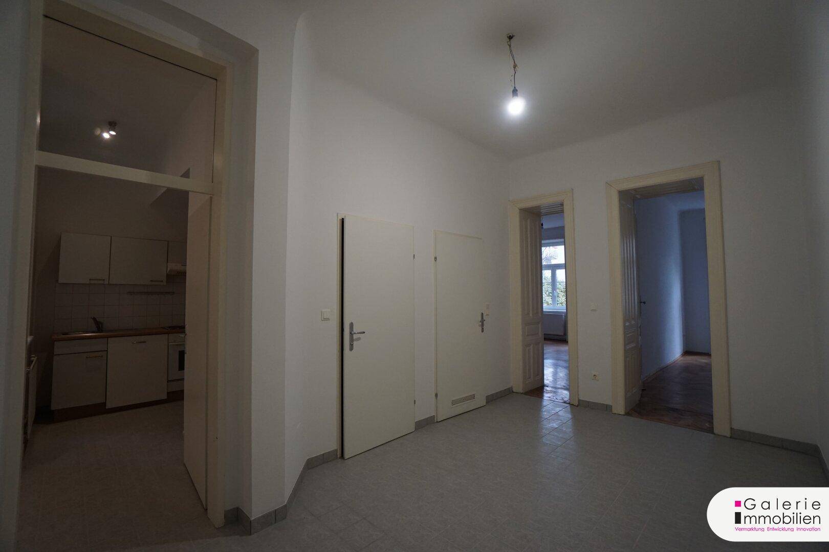 Heller Flur mit mehreren Türen und Blick in eine angrenzende Küche.