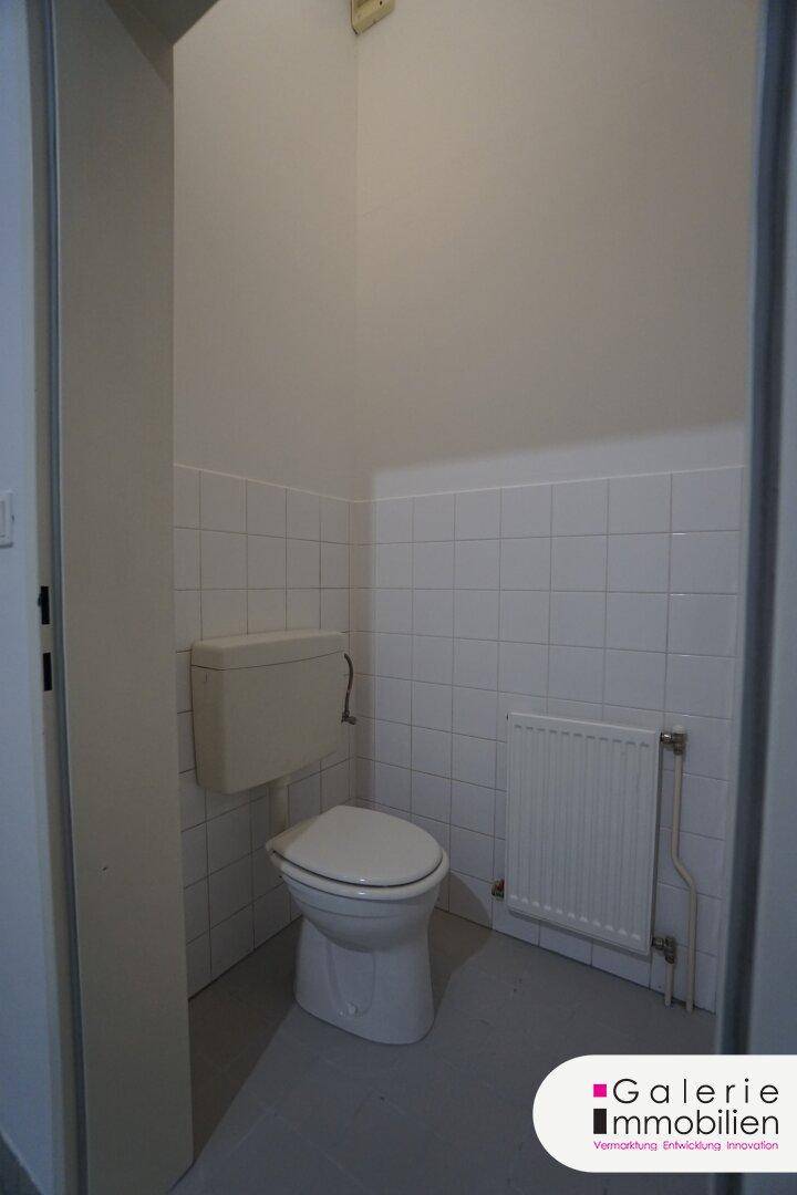 Kleines Gäste-WC mit weißen Fliesen und einfacher Toilette.