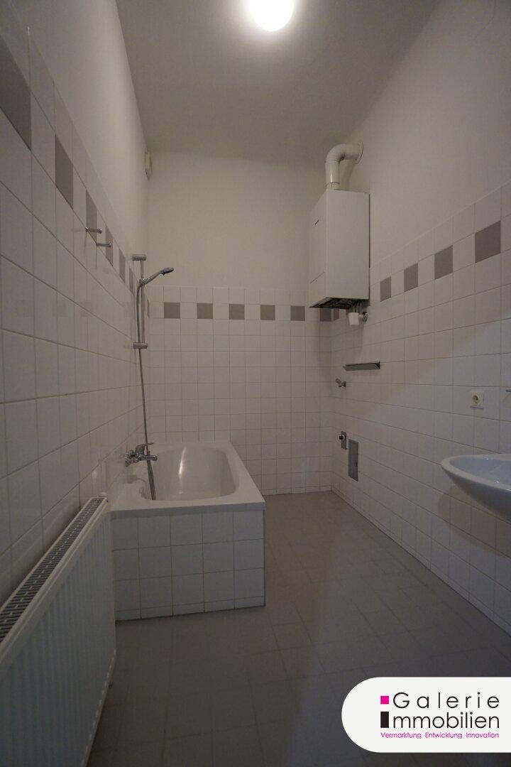 Helles Badezimmer mit Badewanne, Waschbecken und Wandfliesen.
