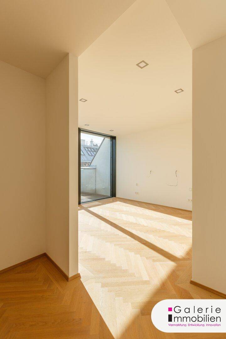 Lichtdurchfluteter Übergangsbereich mit Fischgrätparkett und Blick auf die umliegende Architektur.