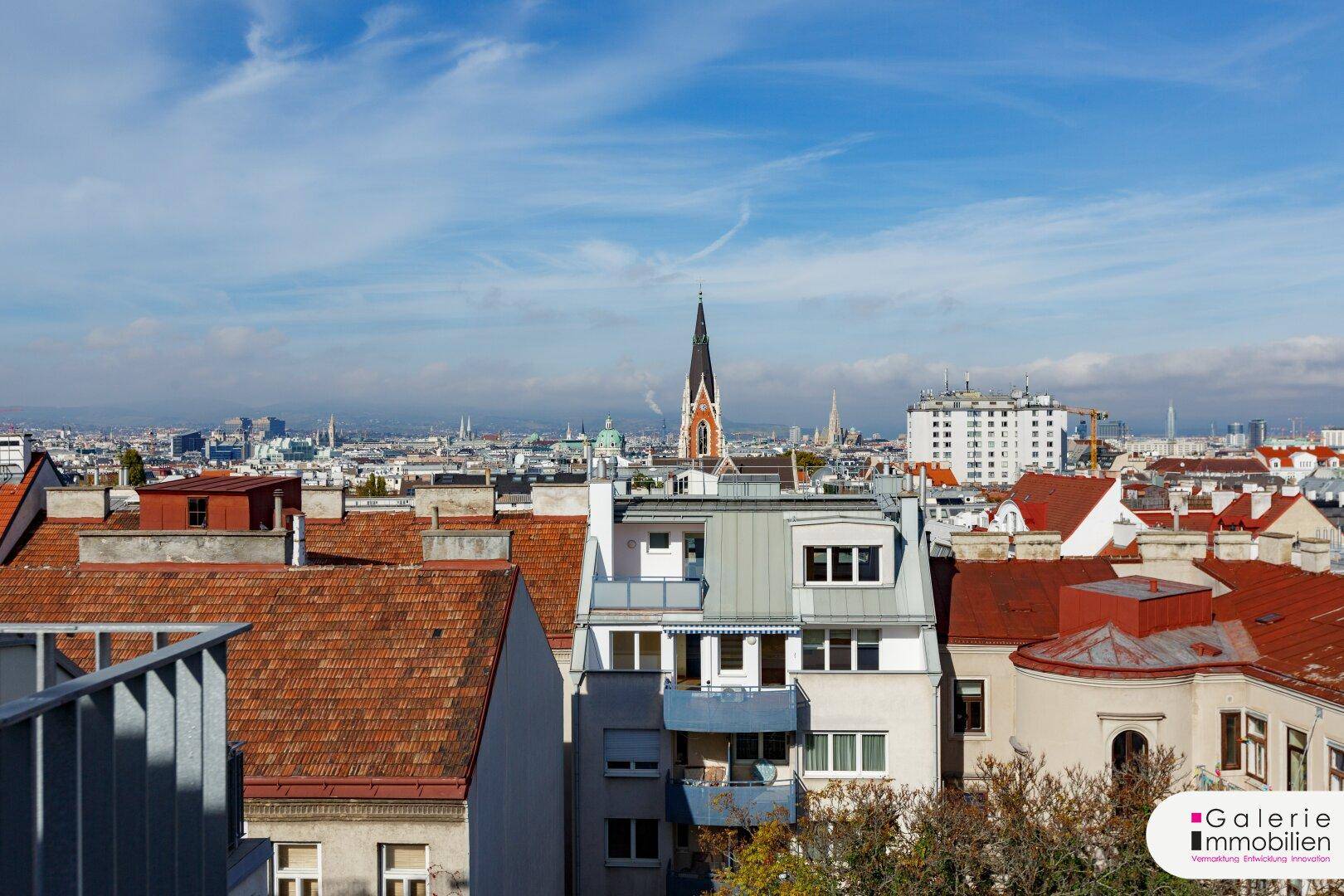 Panoramablick über die Dächer der Stadt mit historischer Kirche unter blauem Himmel.