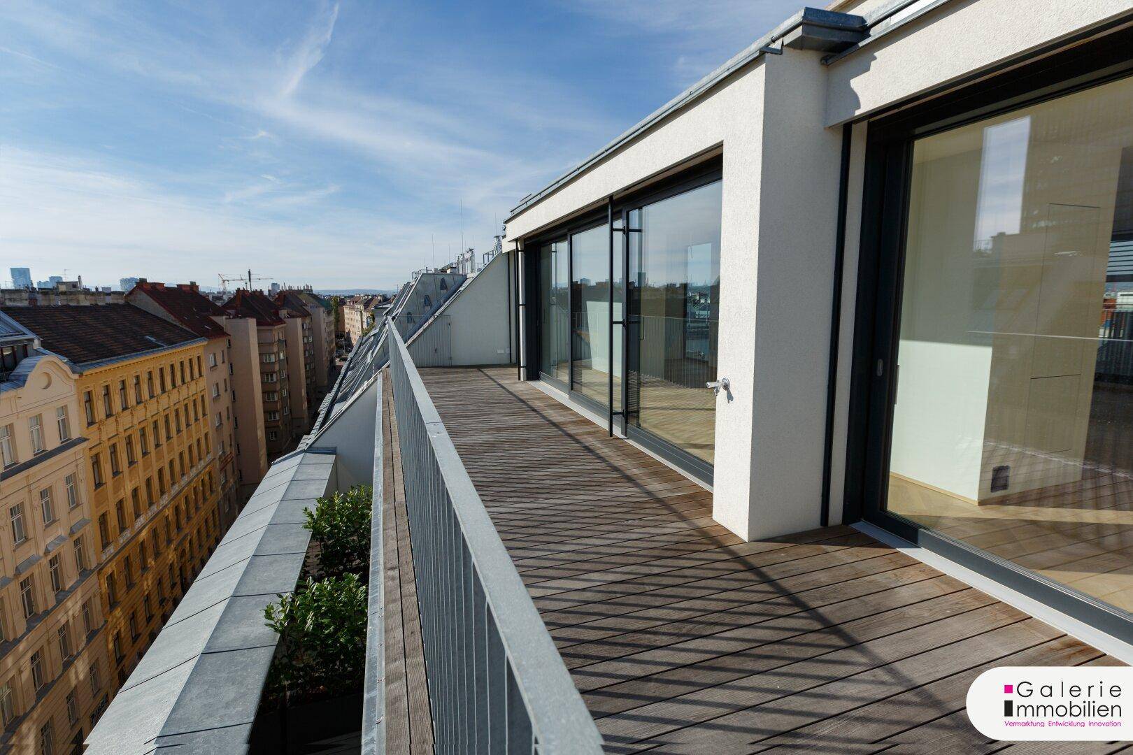 Weitläufige Terrasse mit Holzboden und Blick auf die Stadt, ideal für Entspannung im Freien.