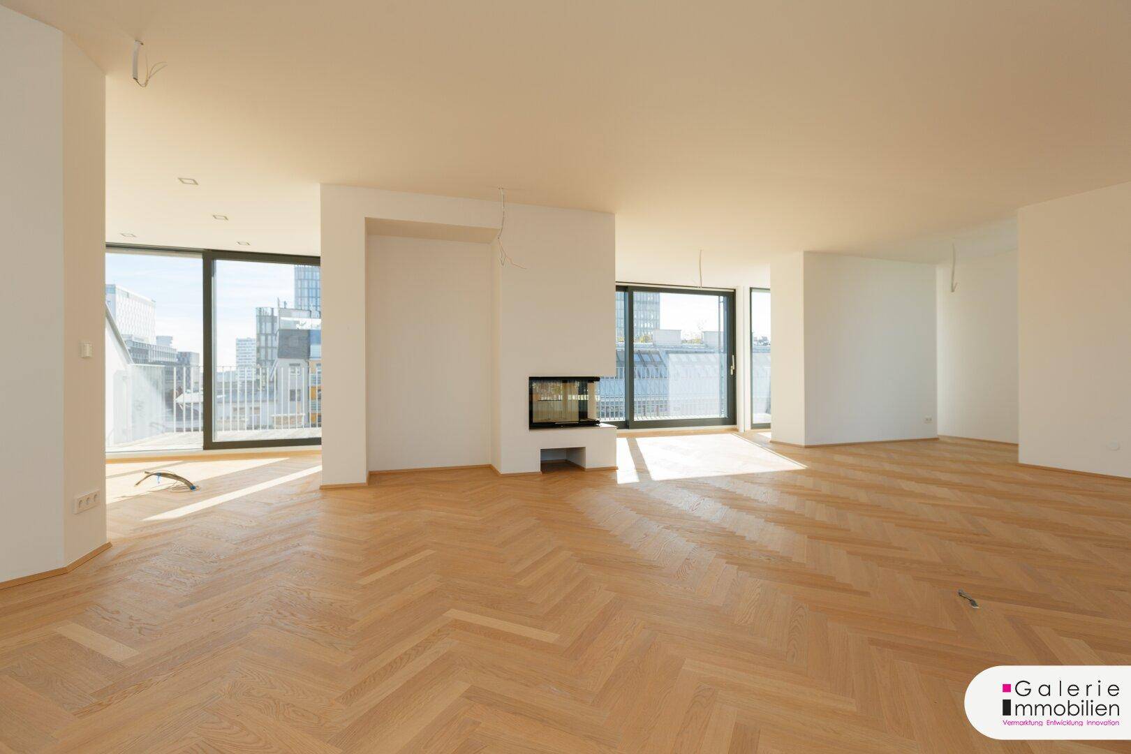 Heller Wohnbereich mit modernem Kamin und großen Fenstern, die einen weiten Blick über die Stadt bieten.