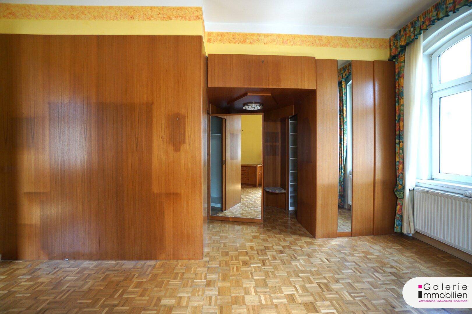 Raum mit Parkettboden und umfangreichen eingebauten Holzschränken und Wandverkleidungen.