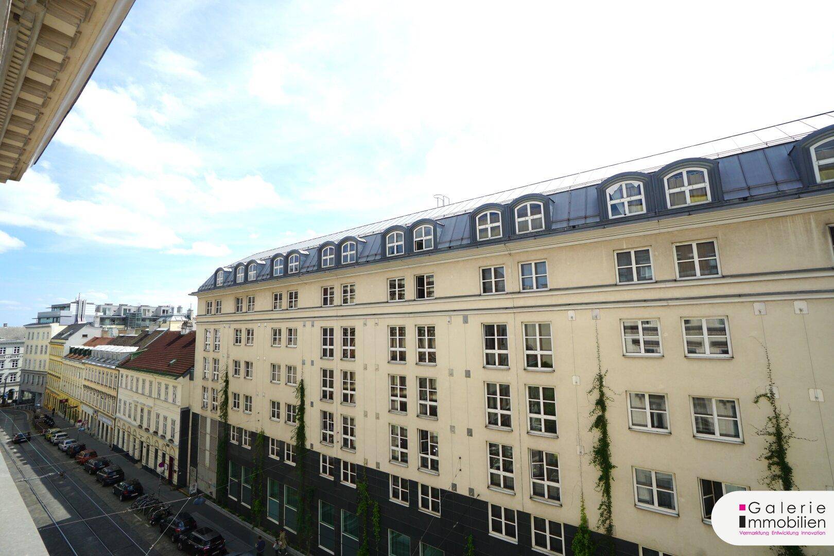 Weitblick über eine Stadtstraße mit Gebäuden und einem klaren Himmel.