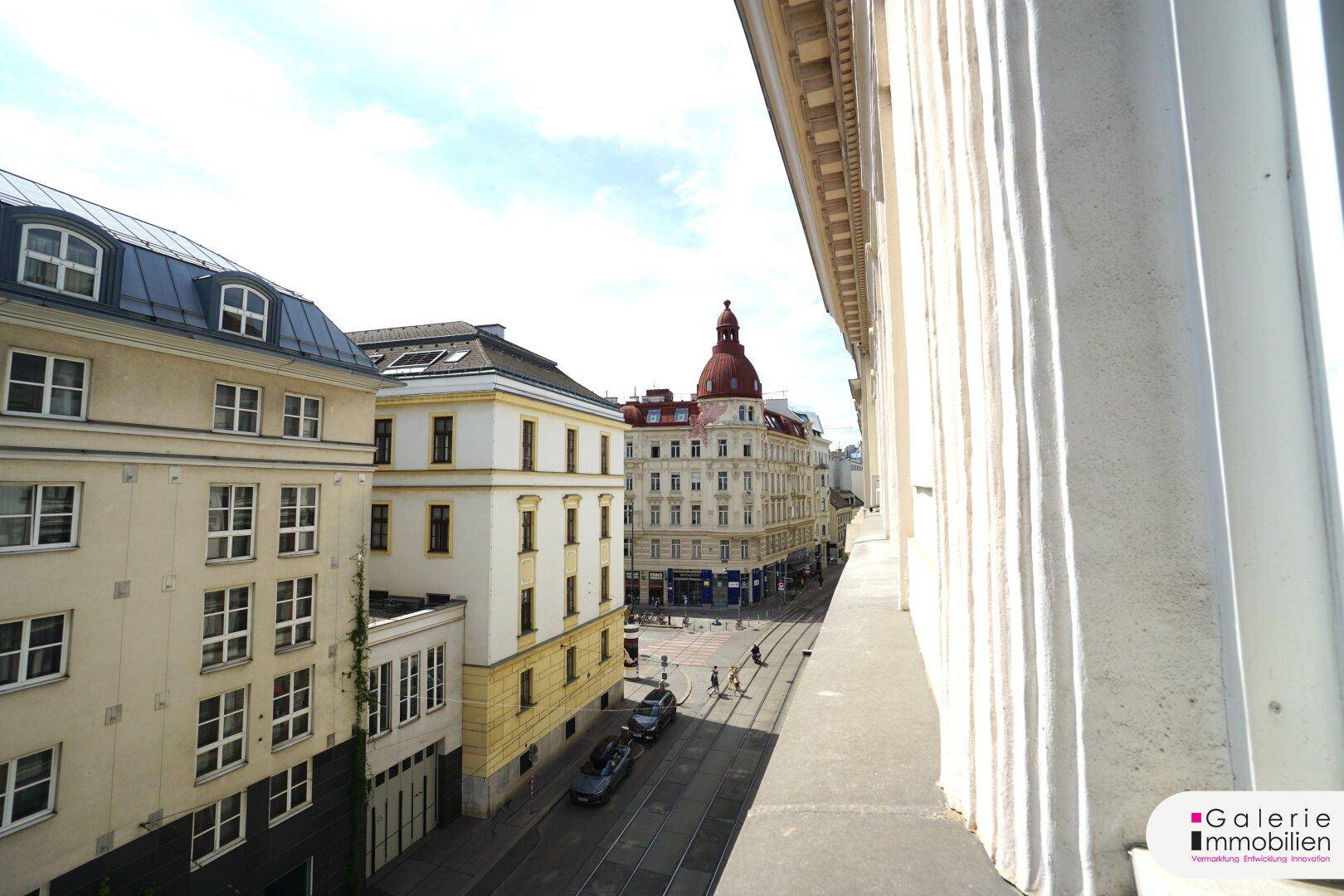 Panoramablick auf eine Stadtstraße mit Gebäuden, Straßenbahn und der Fassade des eigenen Gebäudes.