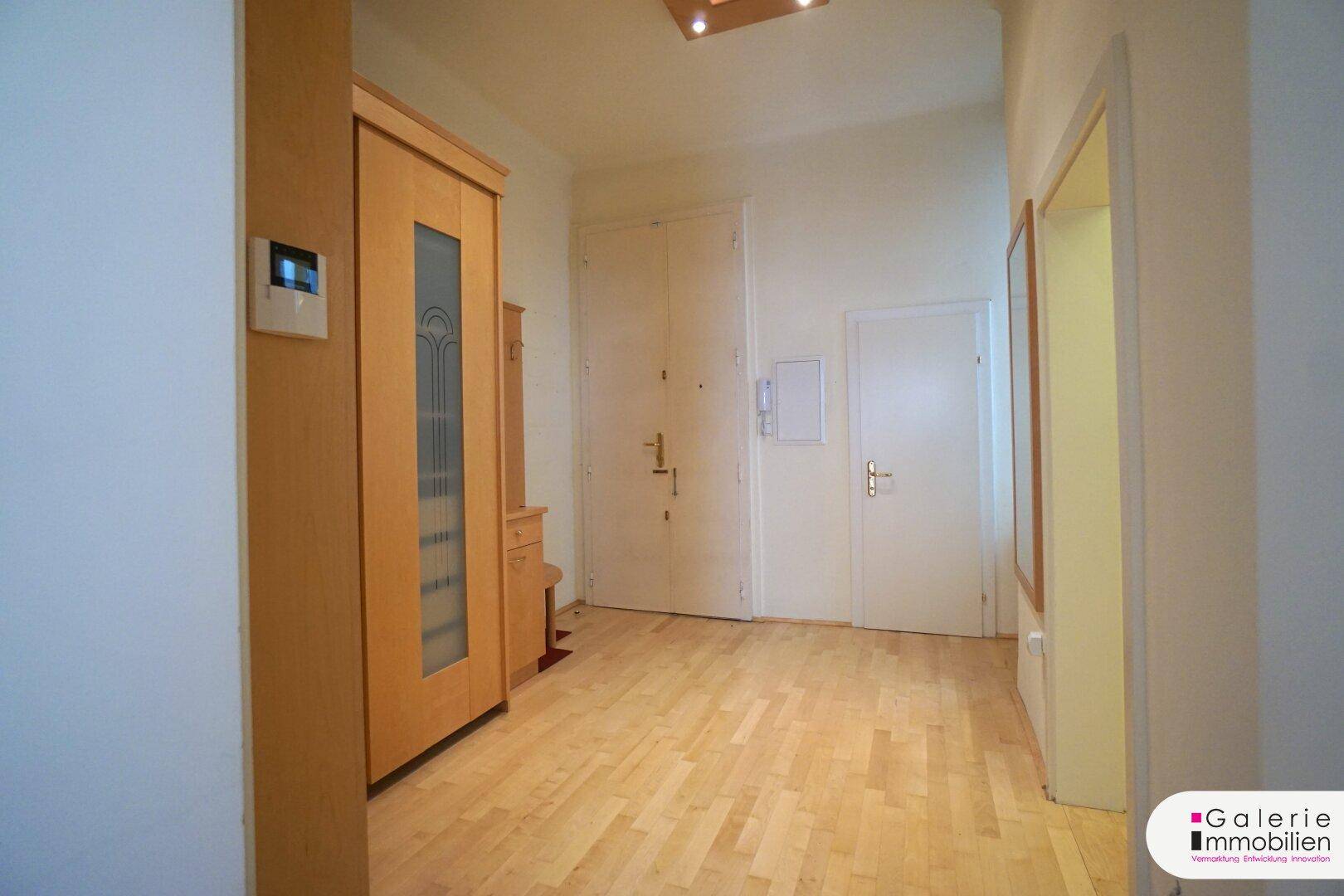 Geräumiger Eingangsbereich mit Holzboden, großem Kleiderschrank und zwei Türen.