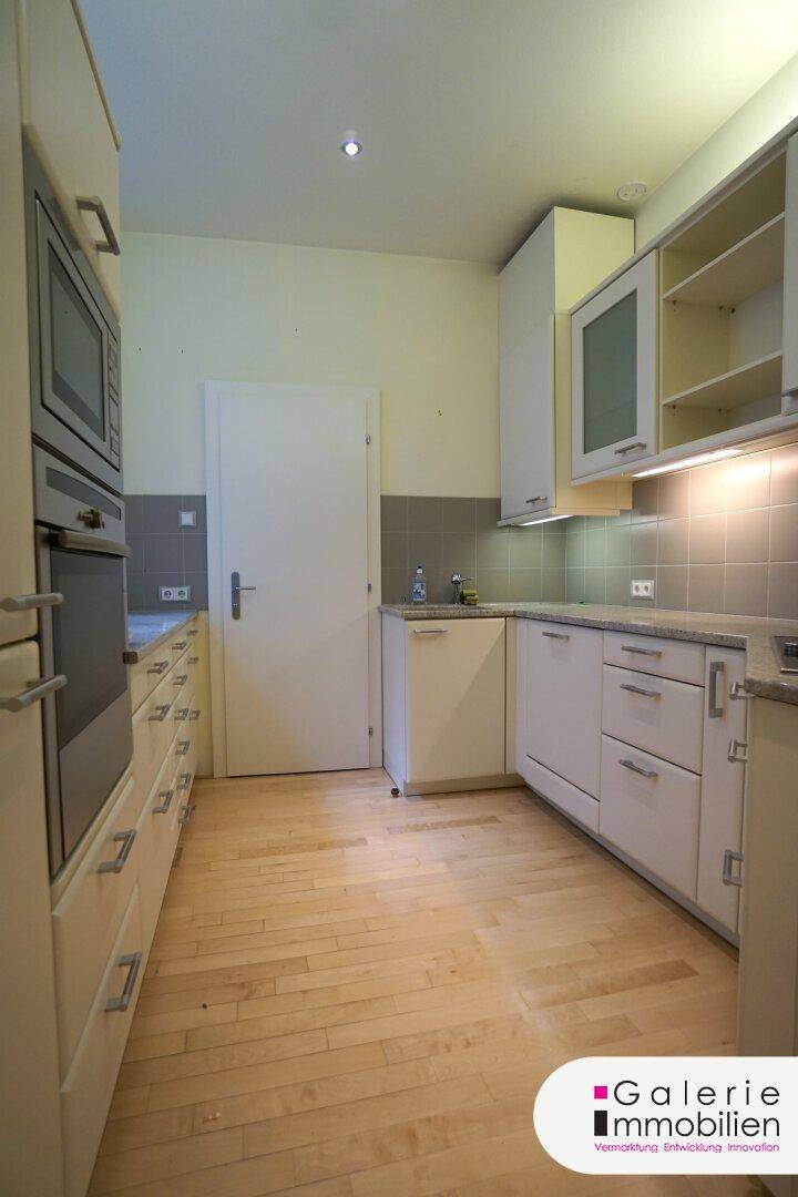 Helle Küche mit Holzboden, modernen Einbauschränken und einer weißen Tür.