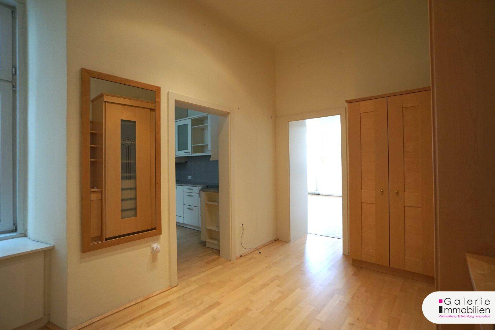 Flur mit Holzboden, Einbauschrank und Zugang zu angrenzenden Räumen, inklusive Küche.