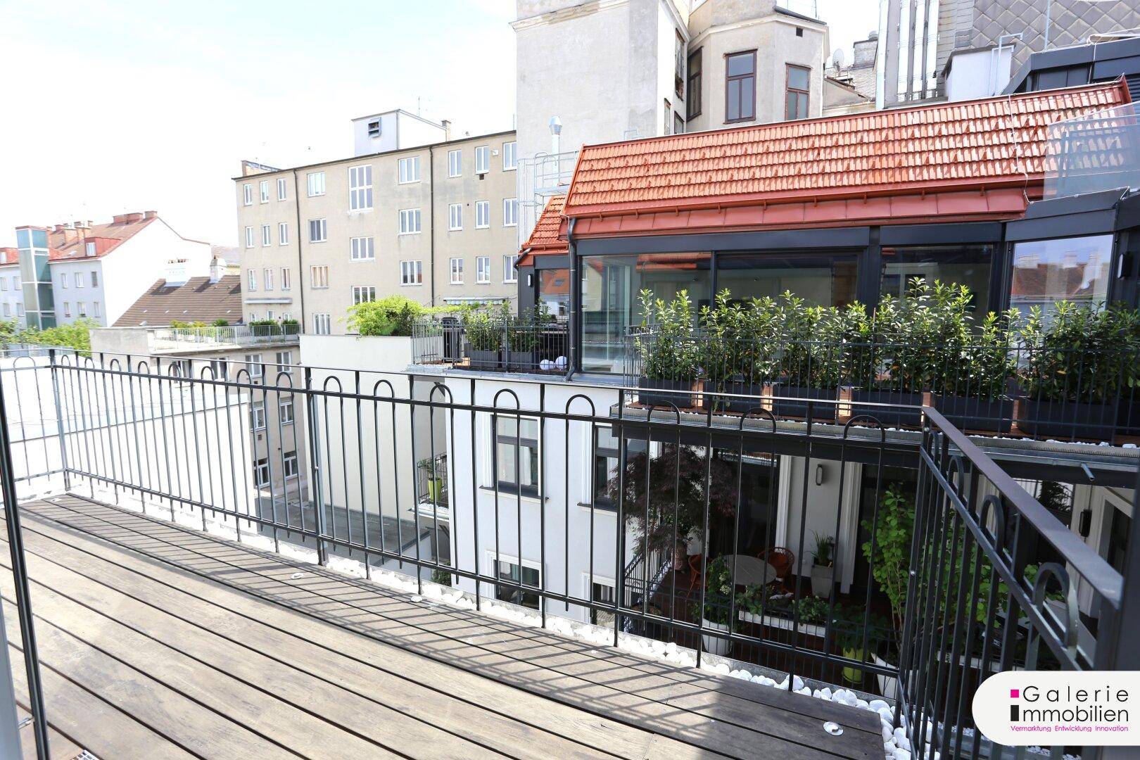 Blick von der Terrasse auf weitere Terrassen und die umliegende Bebauung mit grünen Pflanzen.