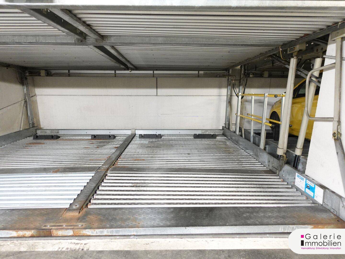 Detailansicht eines automatischen Parksystems in einer Tiefgarage mit einem gelben Fahrzeug.