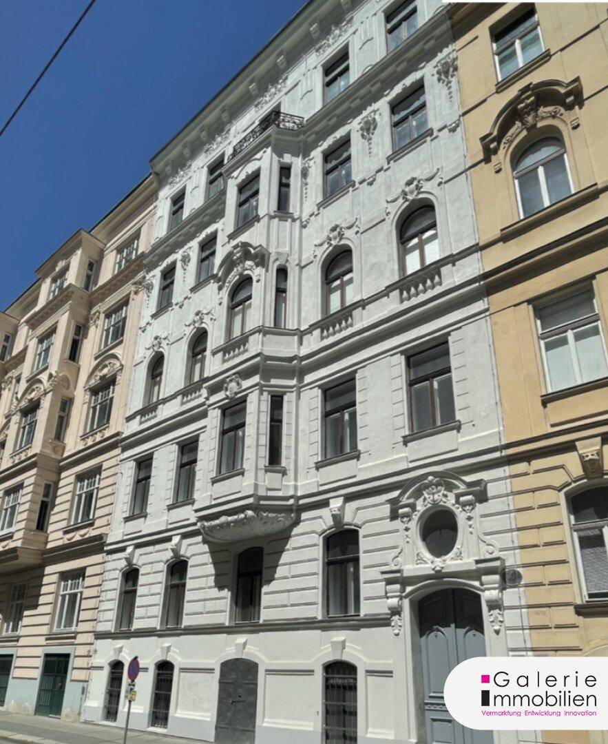 Historisches Gebäude mit eleganter Stuckfassade, Erkern und kleinem Balkon unter blauem Himmel.