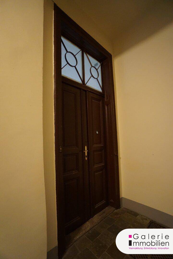 Klassische Holztür mit Oberlicht und verzierten Glaseinsätzen im Eingangsbereich.