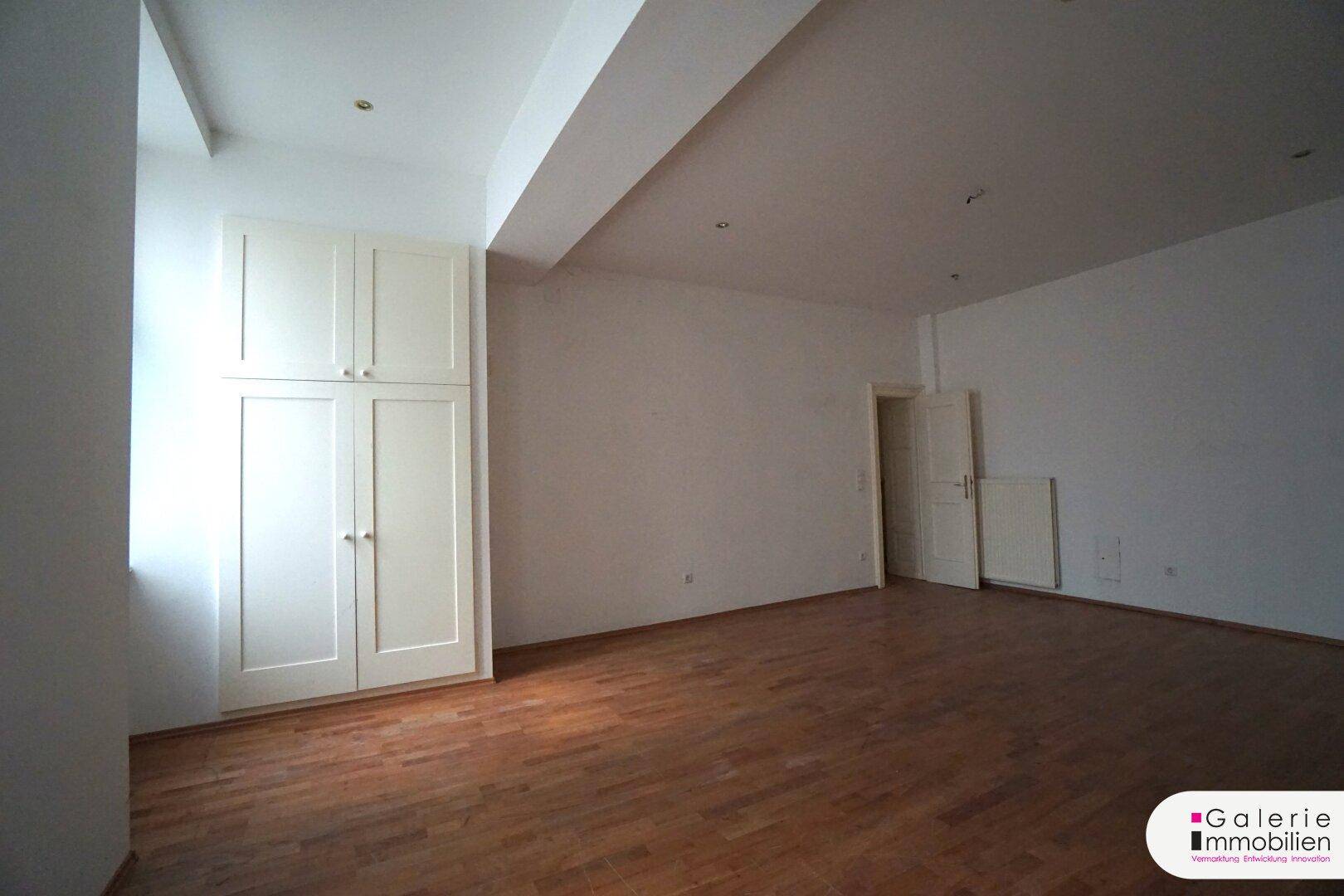Helles Schlafzimmer mit Holzboden und einem großen Einbauschrank an der Wand.