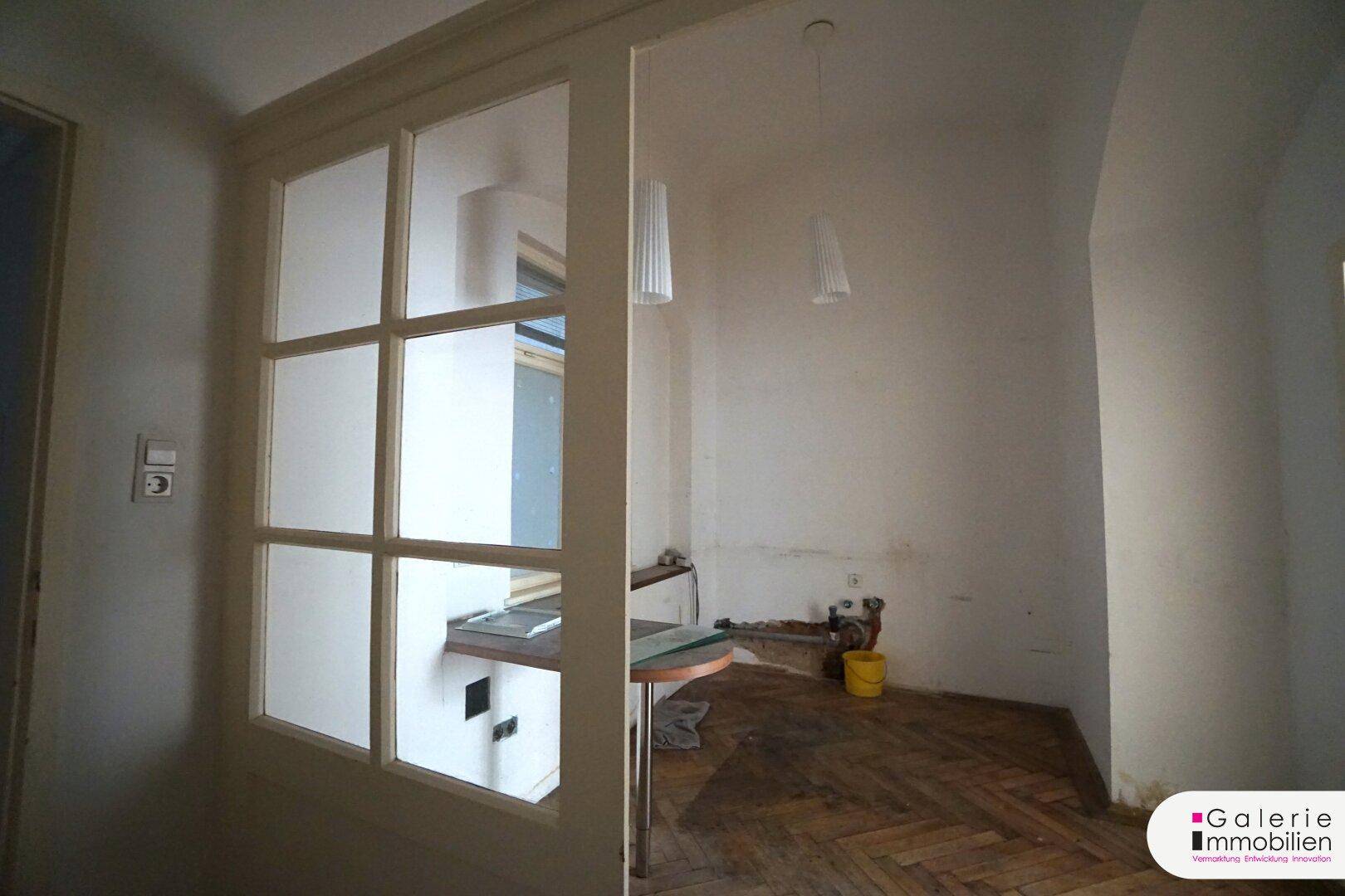 Raum, der als Küche vorgesehen ist, mit Fenster, Arbeitsplatte und Anschlüssen.