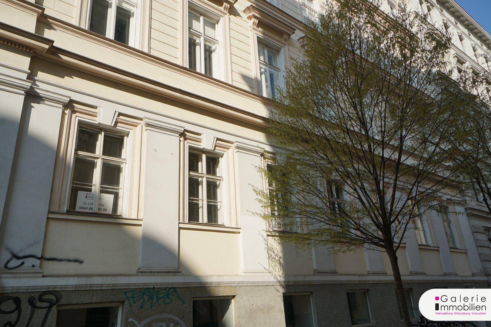 Detailansicht der historischen Fassade eines Altbaus mit Fenstern und Graffiti im unteren Bereich.