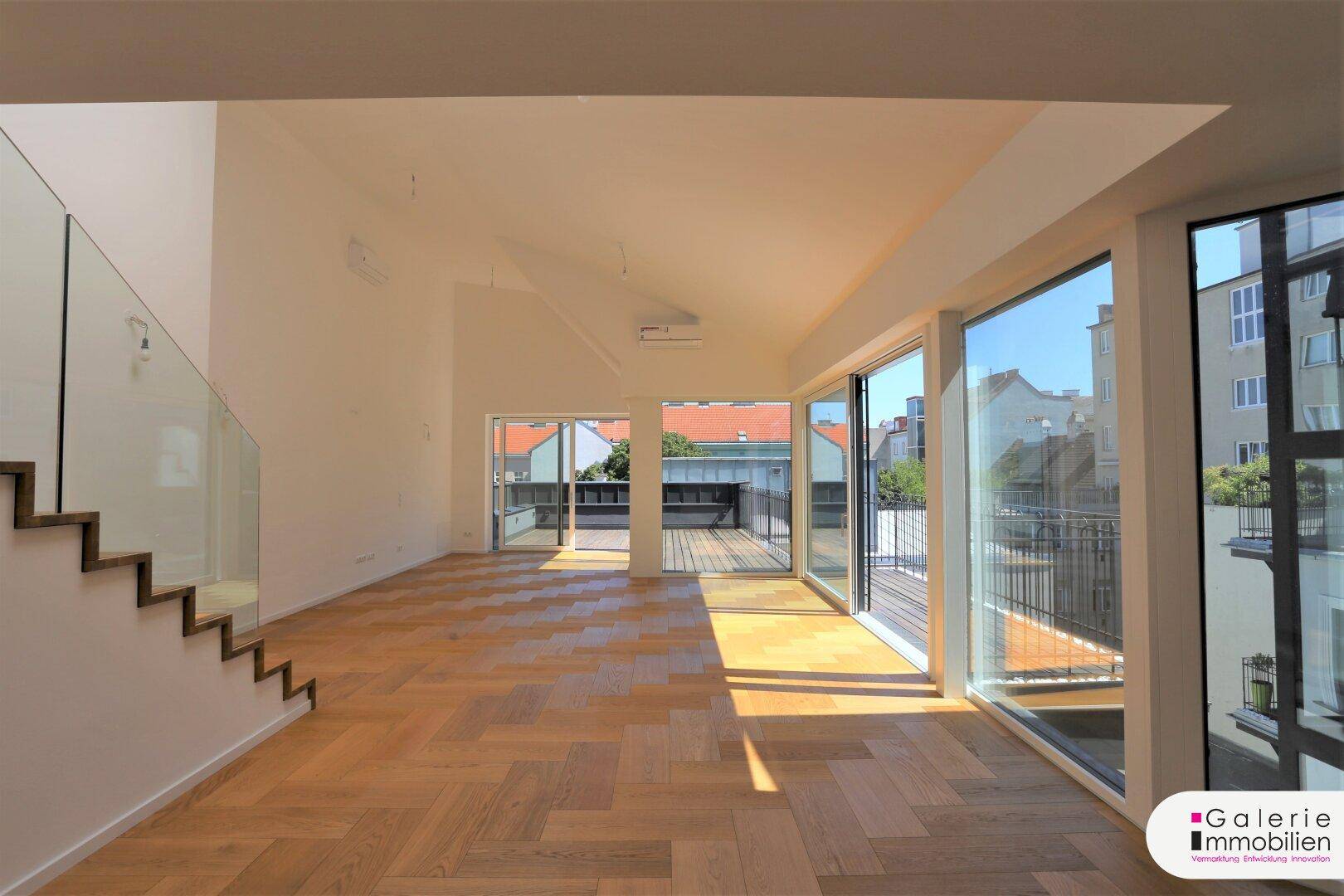 Helles, geräumiges Wohnzimmer mit Fischgrätparkett, moderner Treppe und Zugang zur Dachterrasse.