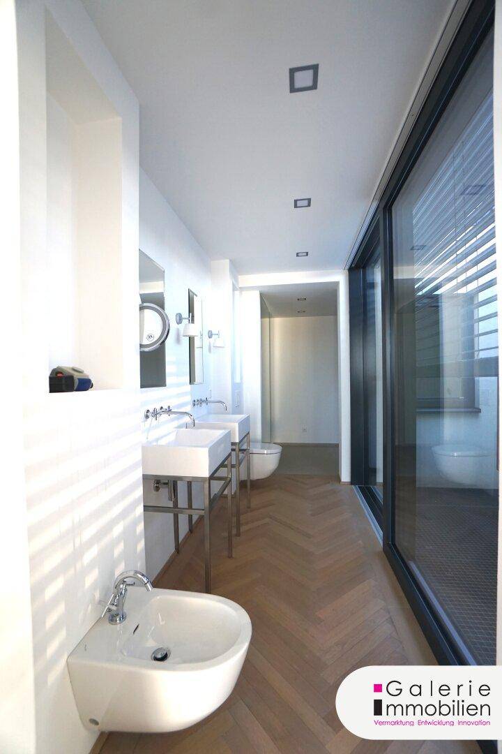 Großzügiges Badezimmer mit mehreren Waschbecken, Bidet und viel Tageslicht.