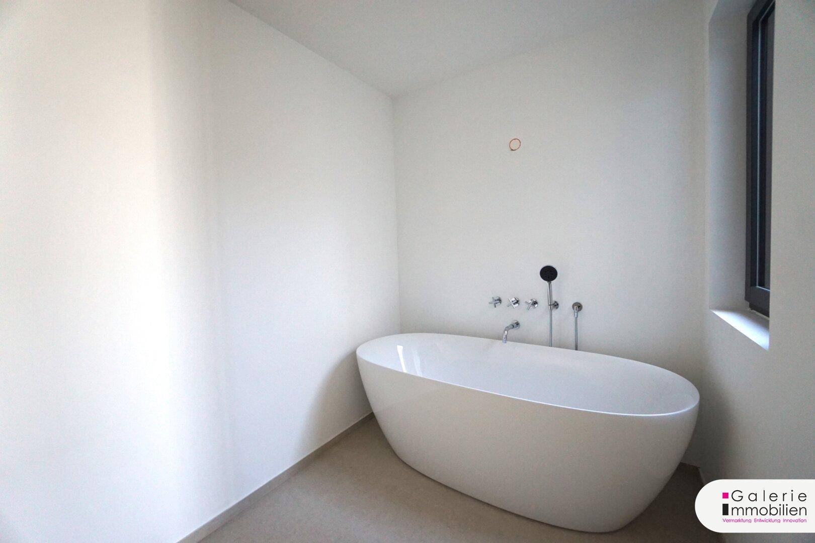 Elegante freistehende Badewanne in einem hellen Badezimmer mit kleinem Fenster.