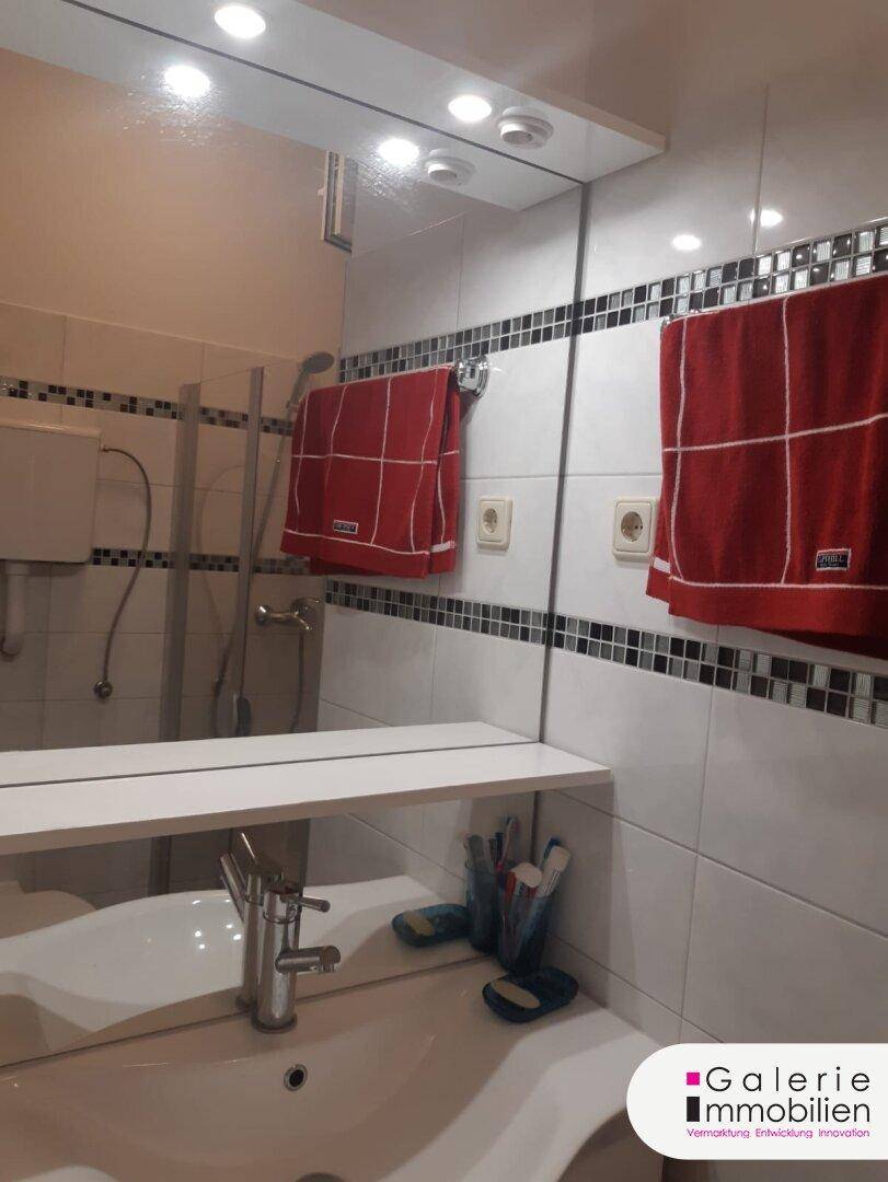 Modernes Badezimmer mit Waschbecken, großem Spiegel und weißen Fliesen.