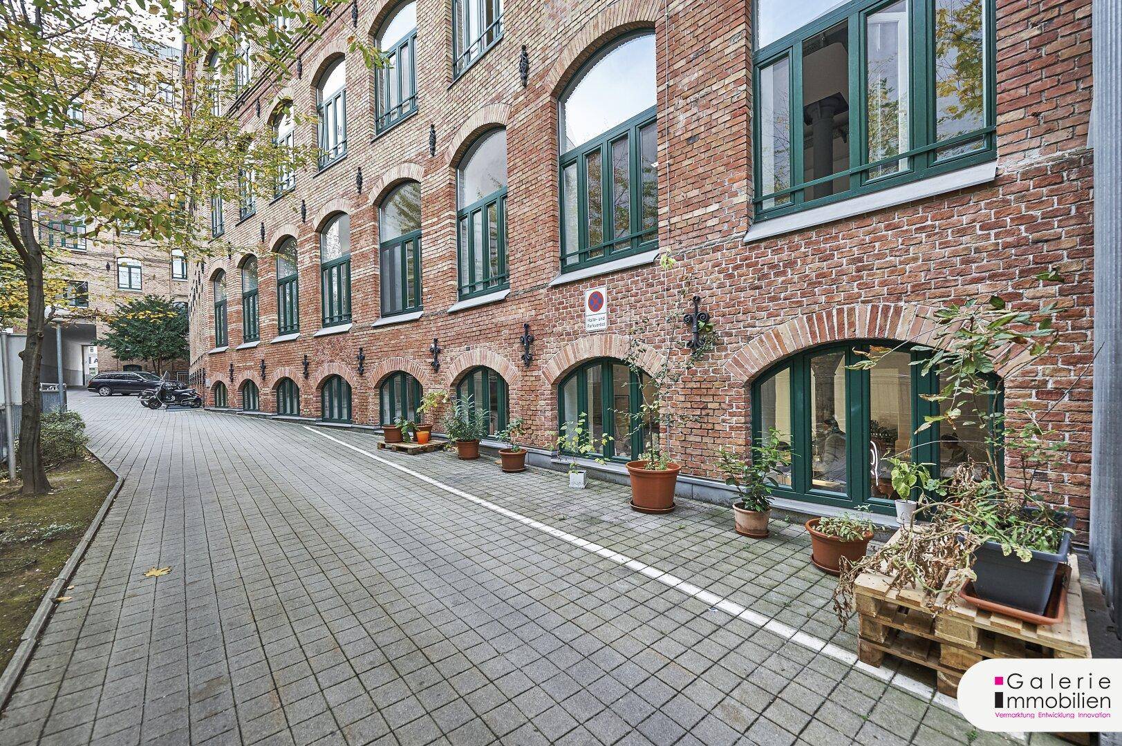 Historische Backsteinfassade mit charakteristischen Rundbogenfenstern und grünen Fensterrahmen.