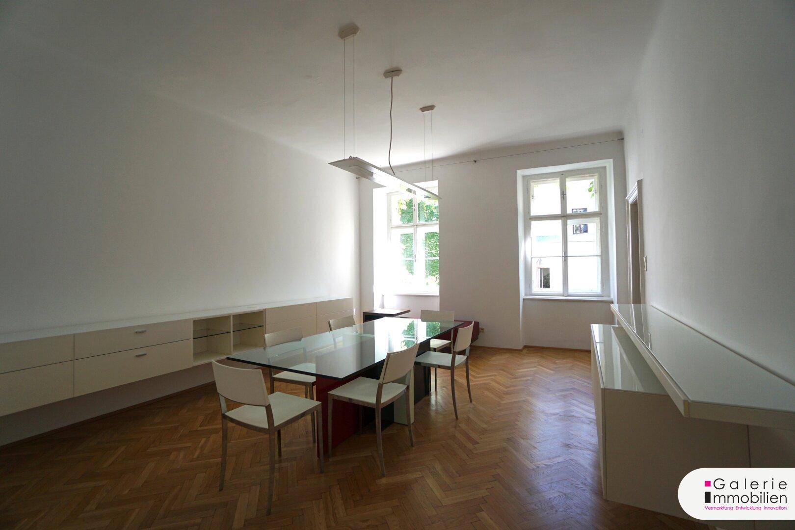 Heller Essbereich mit großzügigen Fenstern, modernem Glastisch und eleganten Wandmöbeln.