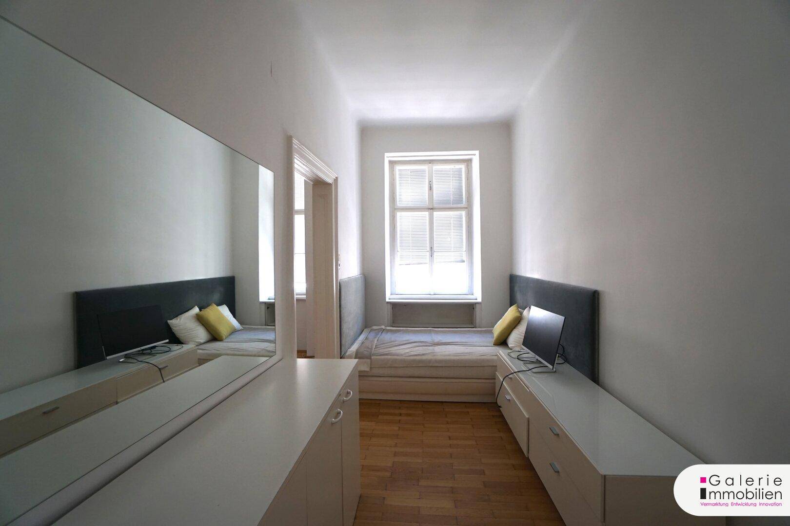 Helles Schlafzimmer mit großem Spiegel, praktischen Kommoden und Fenster.