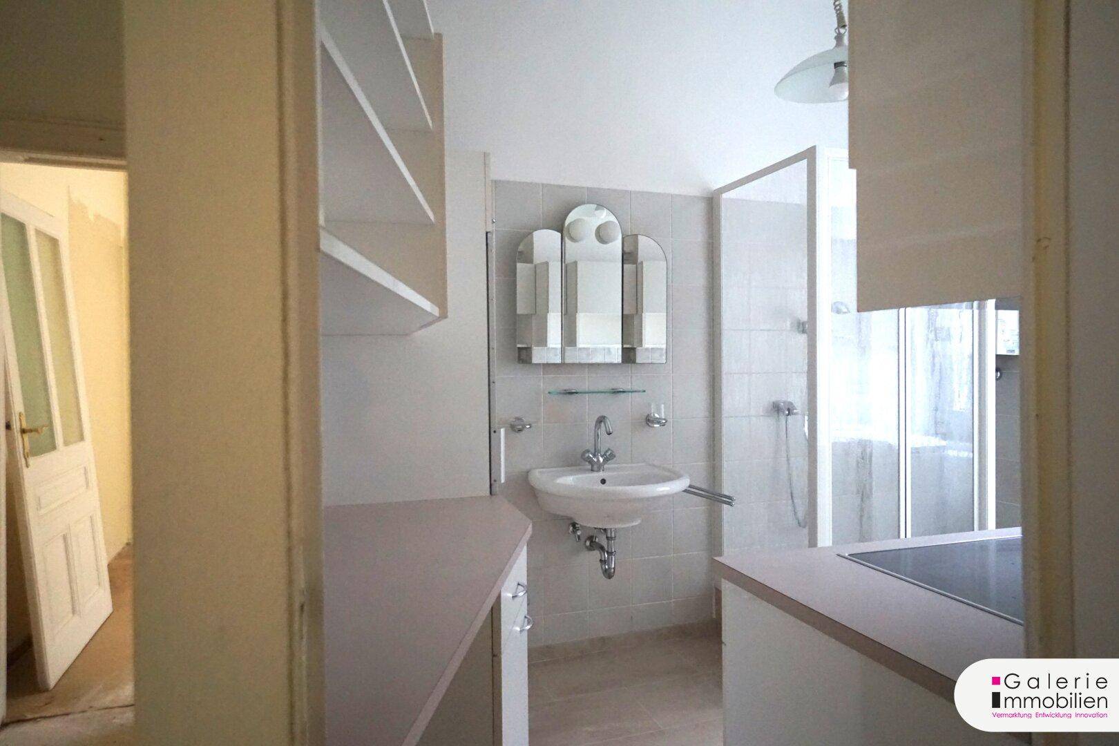 Badezimmer mit Waschbecken, Spiegelschrank und Duschbereich, in einfachem Zustand.