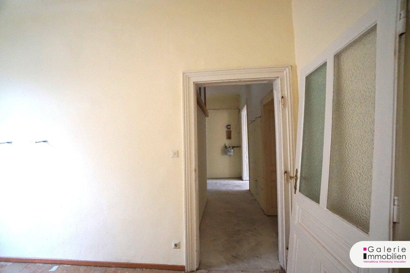 Langer Flur mit Türen und Blick in einen hinteren Bereich des Apartments.