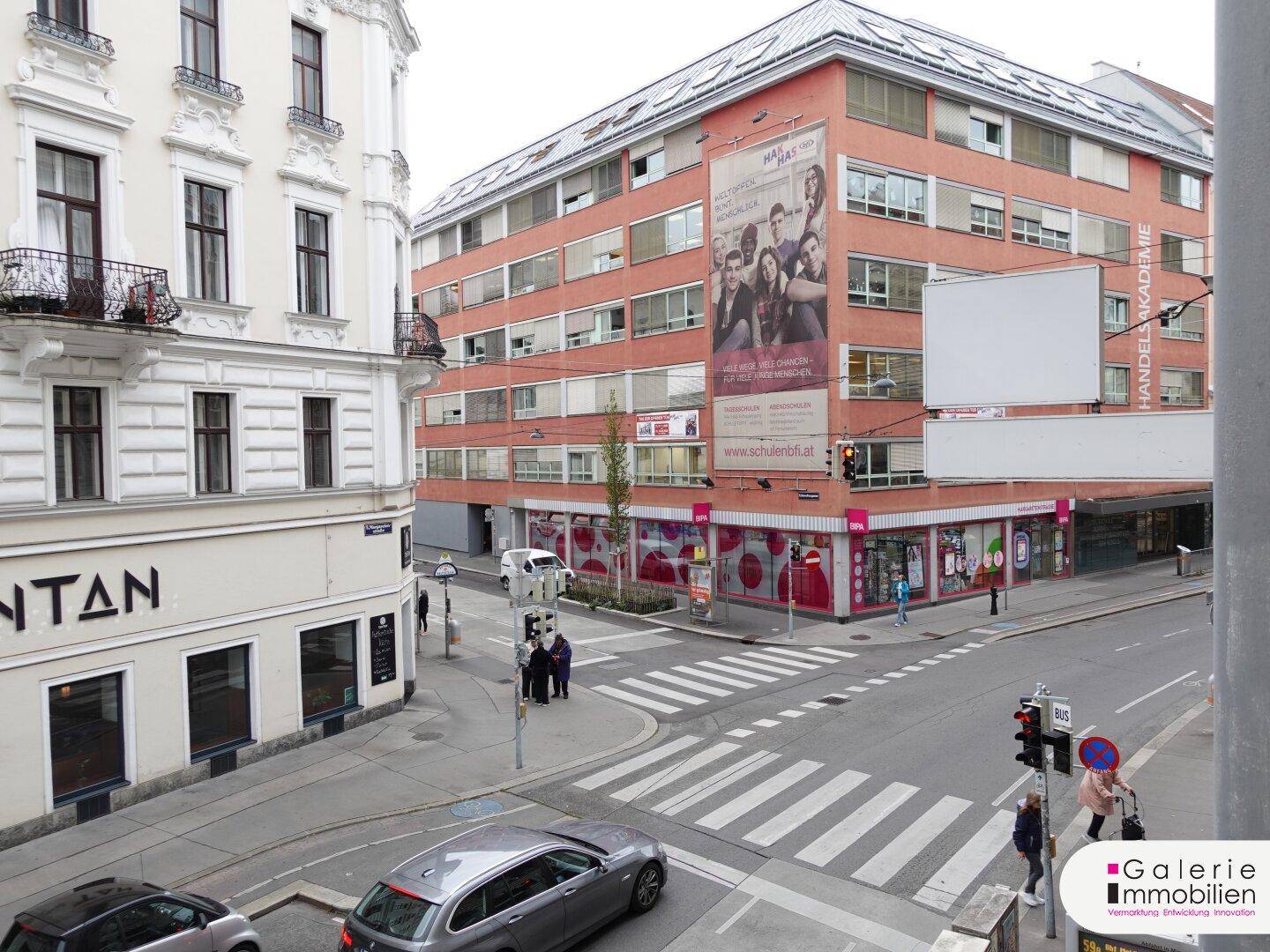 Blick auf die belebte Stadtstraße mit umliegenden Gebäuden und Verkehr.