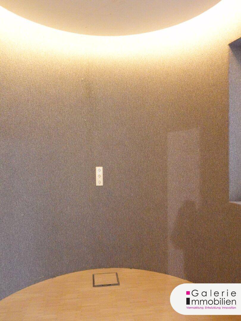 Raum mit einer eleganten, geschwungenen Wand und indirekter Deckenbeleuchtung.
