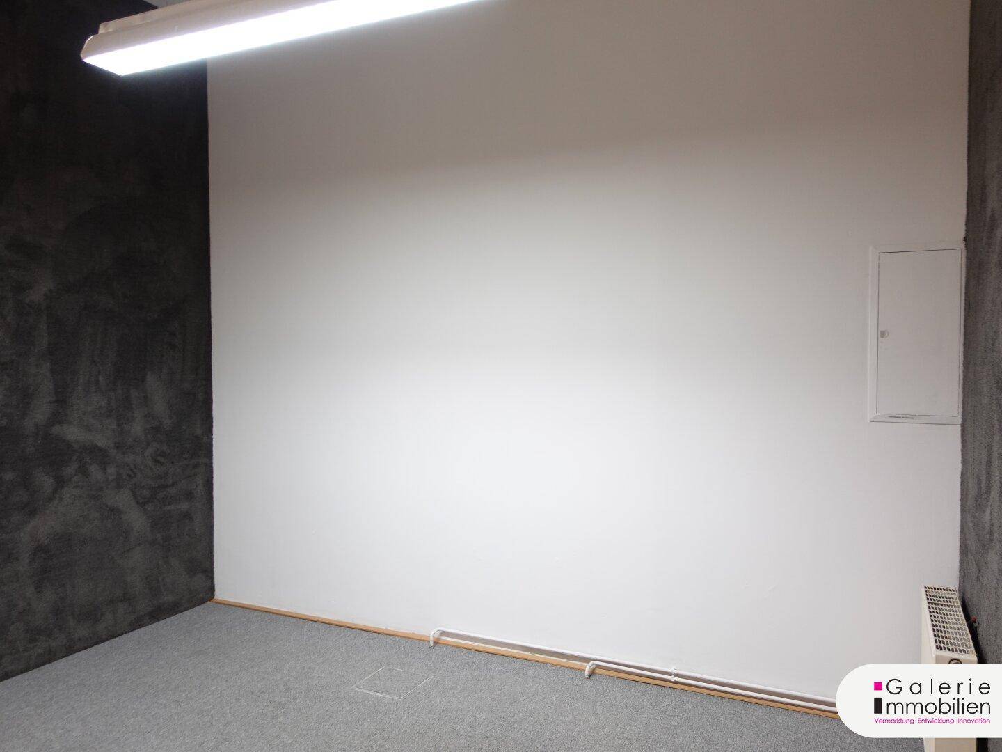 Leerer Raum mit Teppichboden und einer dunklen Akzentwand.