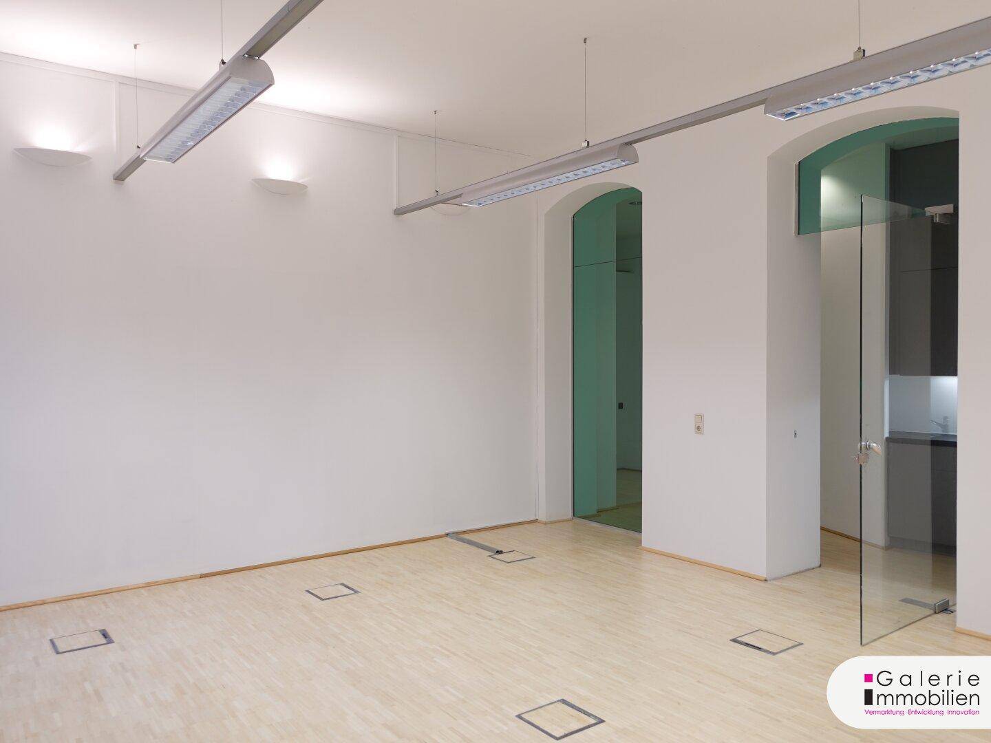 Heller Raum mit Holzboden und modernen Glasabtrennungen zu angrenzenden Bereichen.