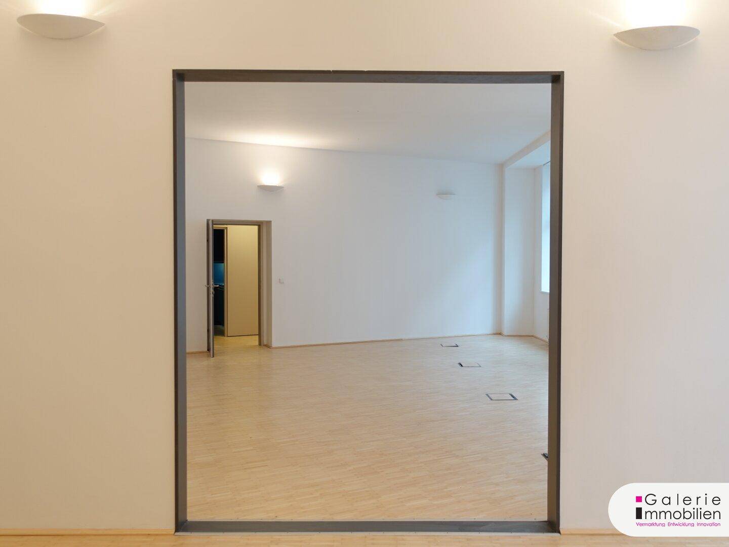 Heller Raum mit Holzboden und einer großen Spiegelfläche, die den Raum optisch vergrößert.