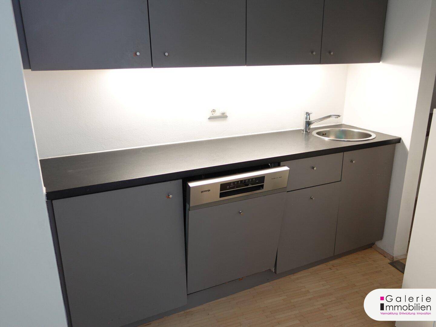 Moderne Küchenzeile in Grau mit Spüle, Geschirrspüler und Arbeitsplatte.