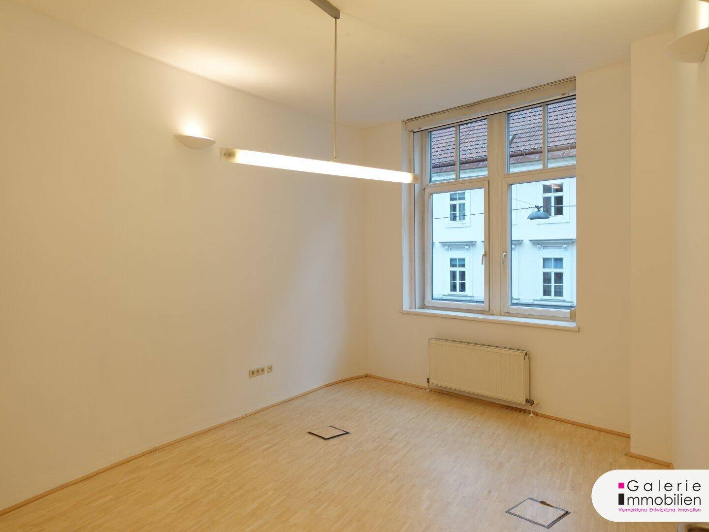 Heller Raum mit einem Fenster, das Tageslicht hereinlässt, und Holzboden.